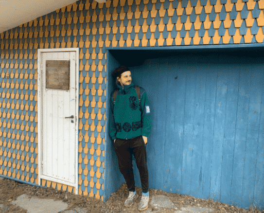 Martin na tle niebiesko-żółtego budynku w Norwegii.